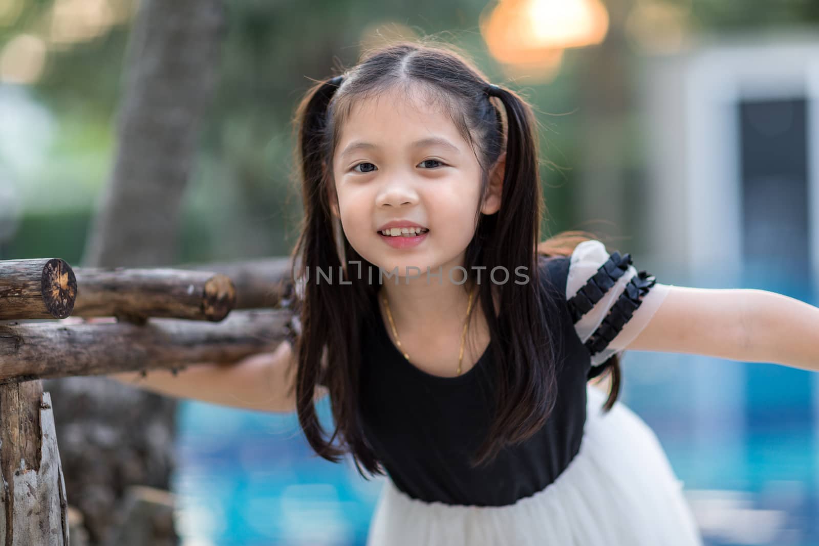 Asian child smiling at outdoor swimming pool.