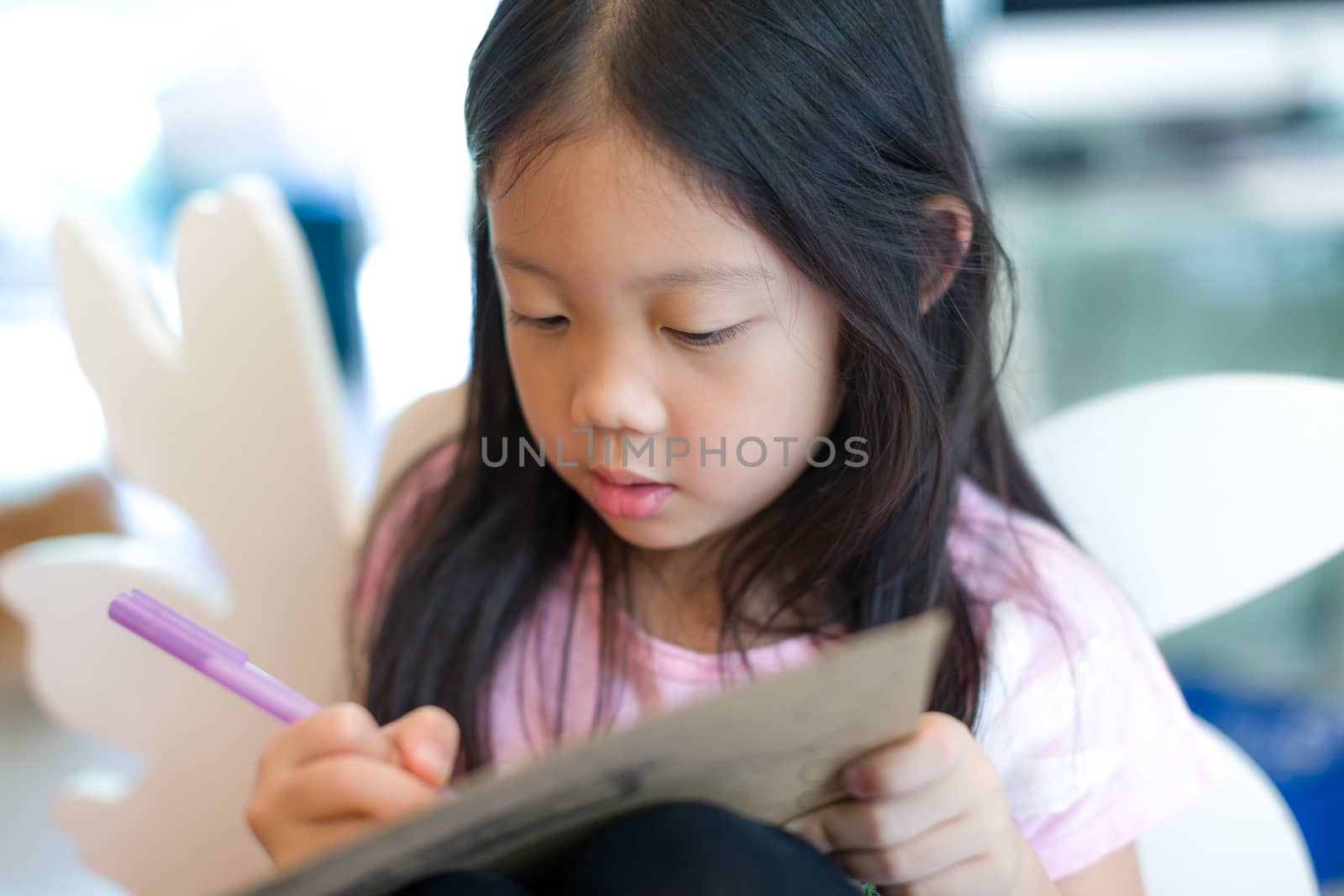 Kid writing or drawing something on notebook.