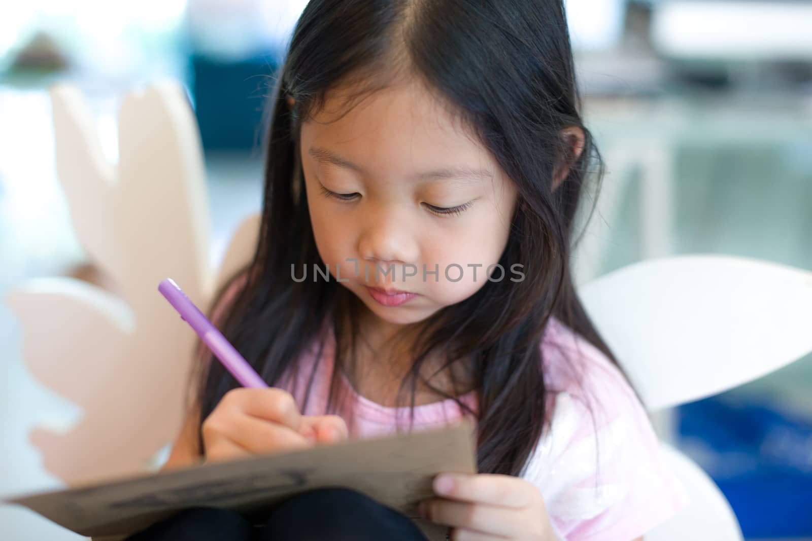 Child writing or drawing something on notebook.