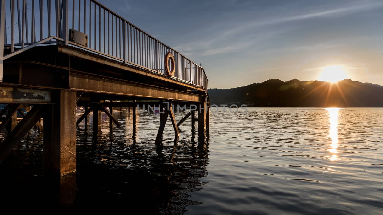 Sunset or sunrise scene of dock at lake and mountain.