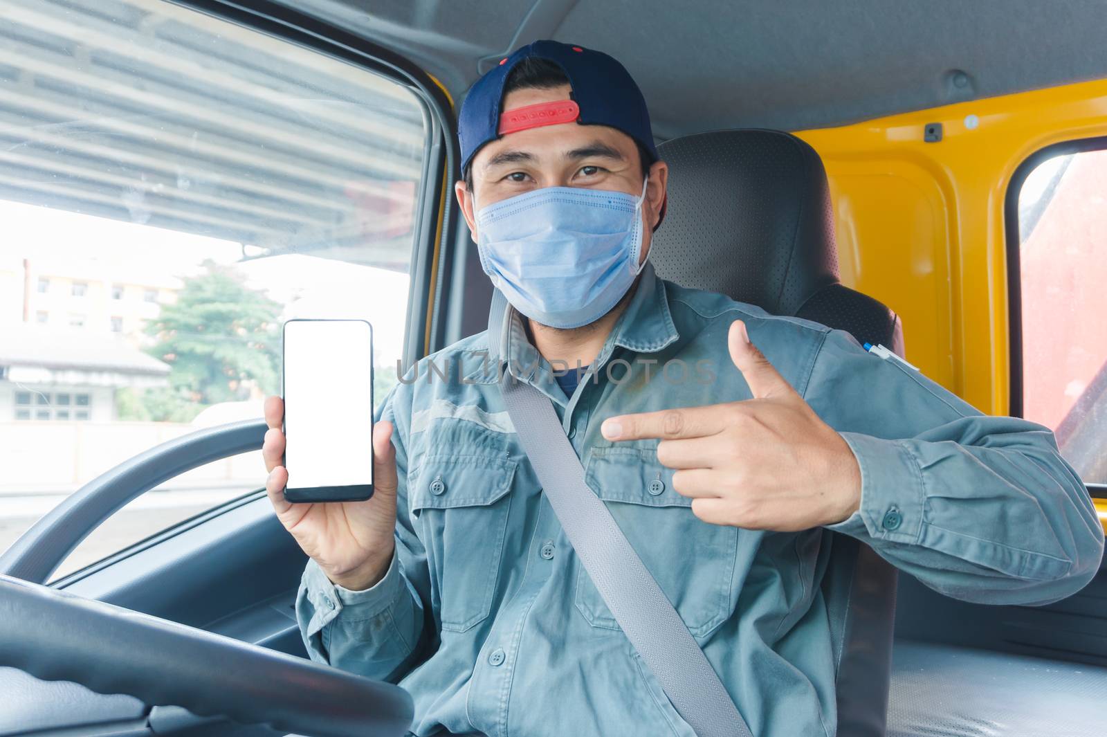 Close-up photos of Asian truck drivers wearing masks to protect against dust and the spread of the flu. Covid 19. Inside the car front.He is using a smartphone to communicate.White screen smartphone