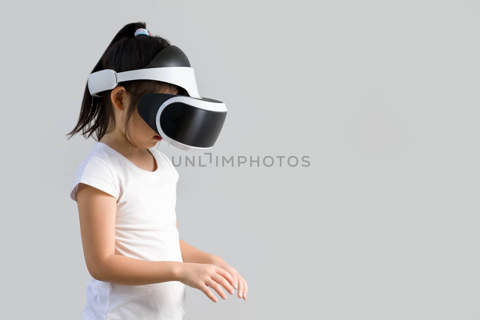 Studio shot of kid with virtual reality, VR, headset, isolated on white background. Child wearing VR goggles to explore digital virtual world.