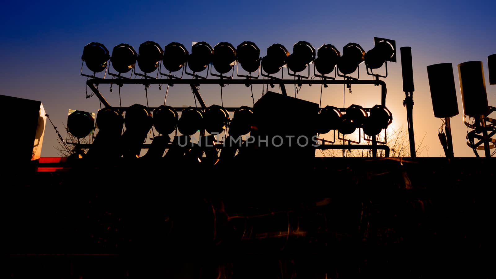 Background of silhouette of concert stage with blue sky and sun light.