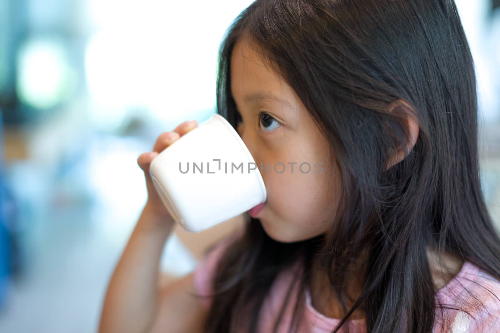 Thirsty Asian child drinking water from cup.