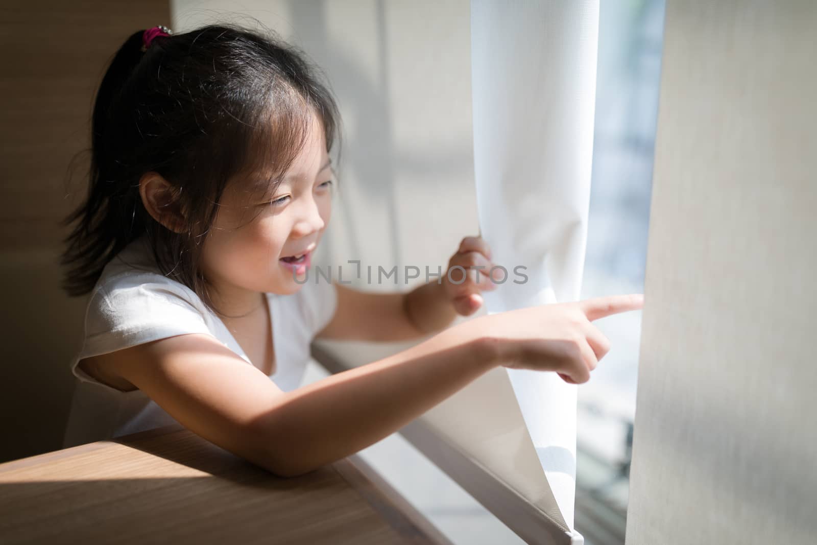 Concept of exploring illustrated by Asian child pointing out and looking out window.