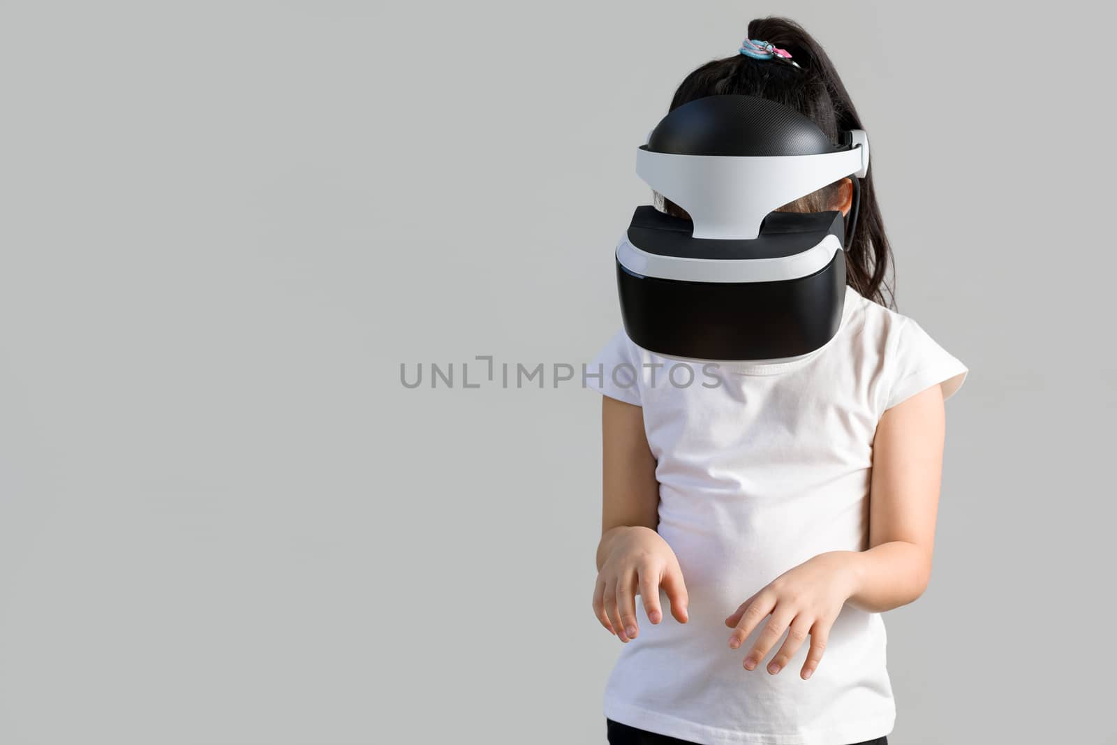 Studio shot of child with virtual reality, VR, headset, isolated on white background. Kid wearing VR goggles to explore digital virtual world.