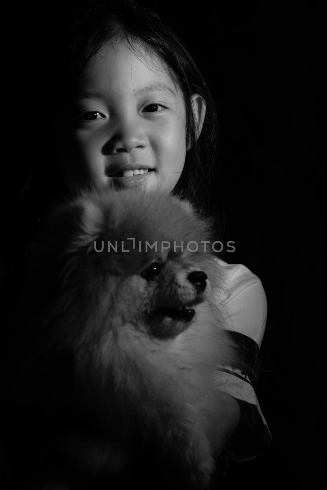 Black and white portrait of Asian child holding dog.