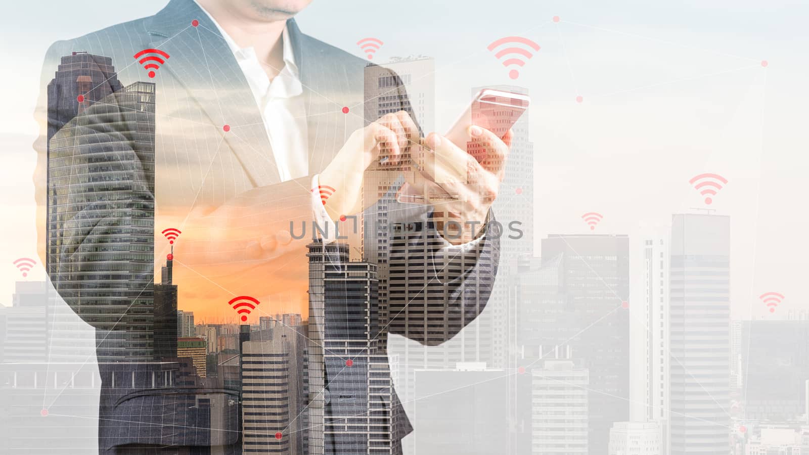 Concept of wireless connection and internet of things, IOT, shown by businessman in suit using smartphone and city as background with double exposure.