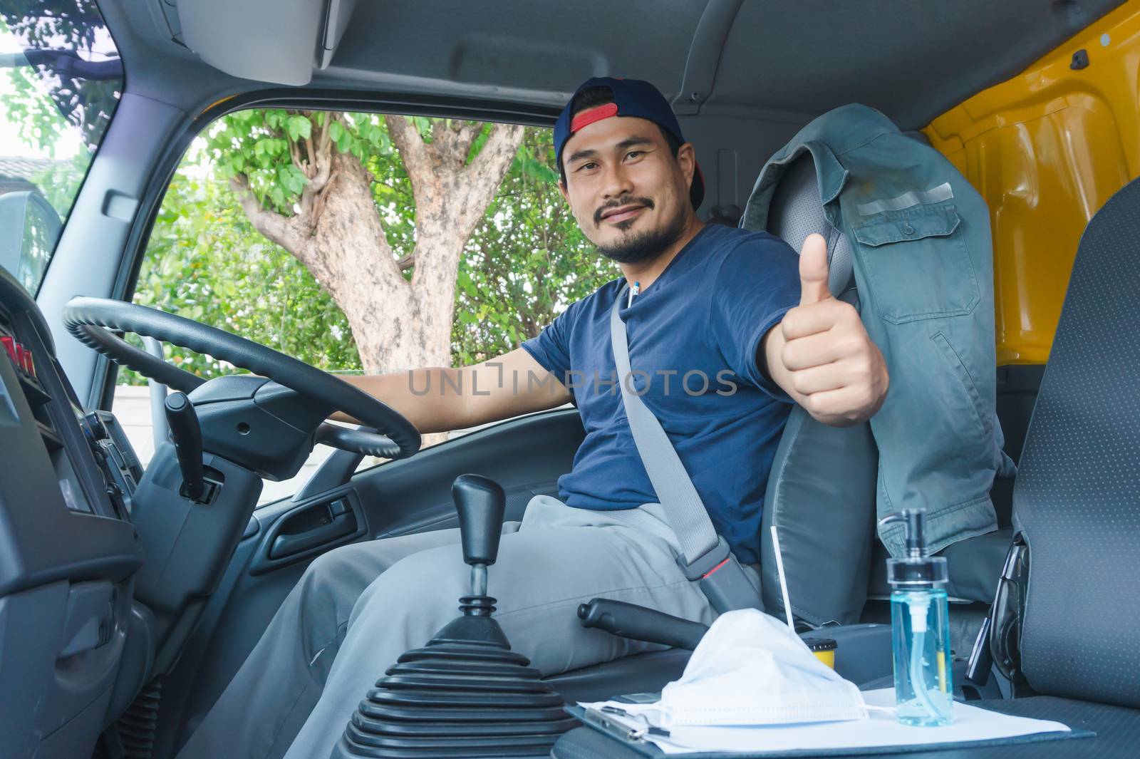 An elderly Asian man is driving a truck to deliver goods to customers. He is the owner of the transportation business.