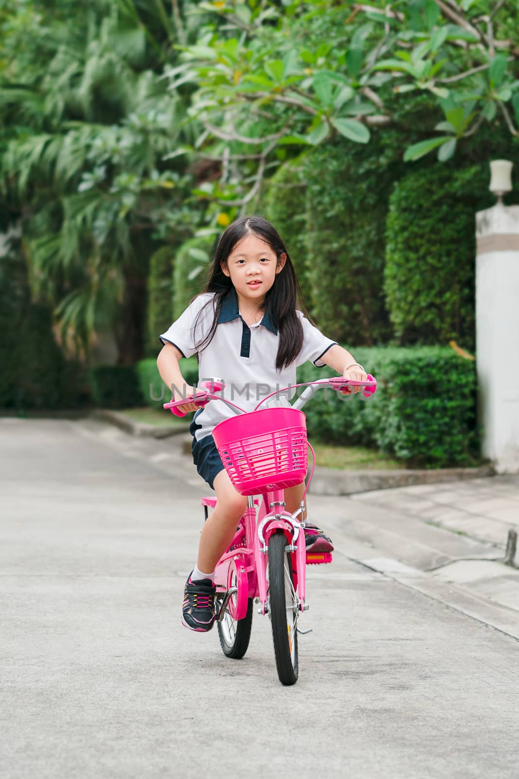 Asian child, girl, riding bicycle on street.
