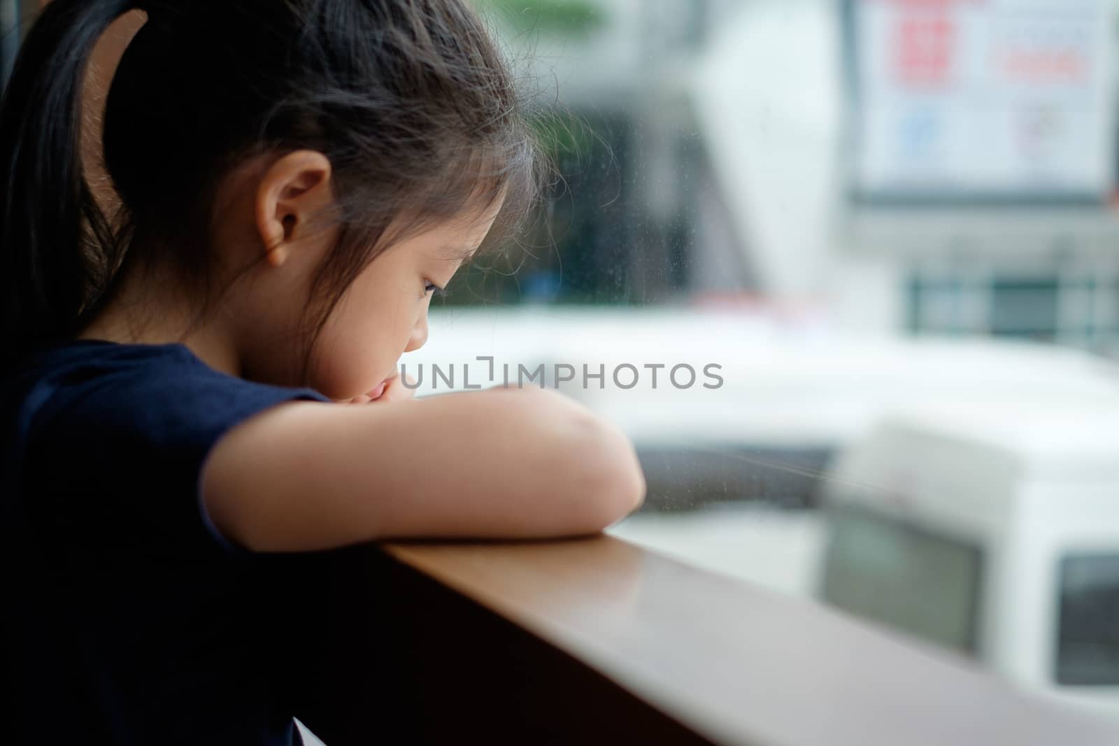 Abandoned sad and lonely Asian child sits next to window.