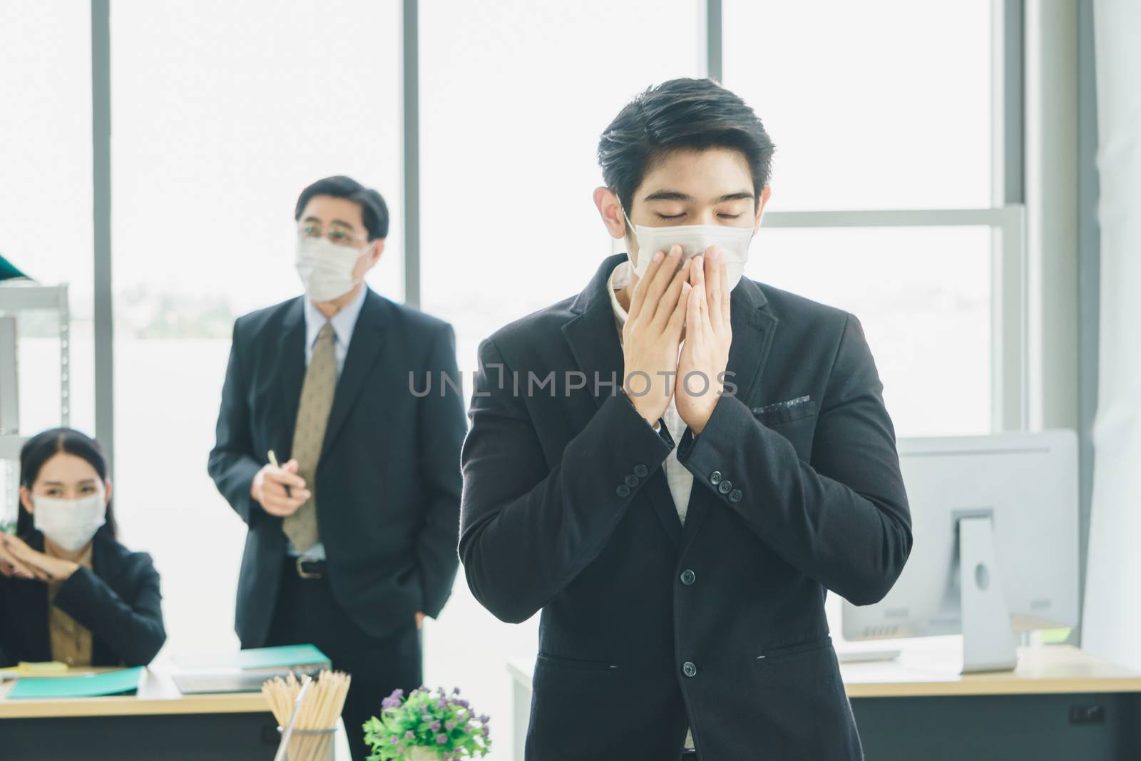 A team of Asian businessmen wear masks to protect and prepare to fight the pandemic virus worldwide. A team of Asian businessmen wearing black suits are working together in the office.