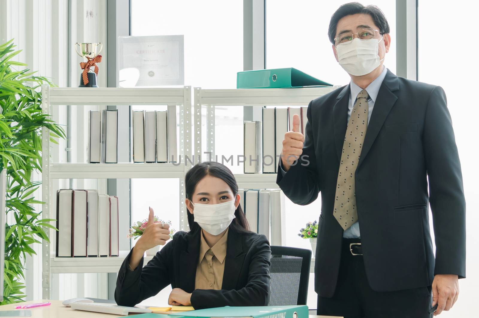 A team of Asian businessmen wear masks to protect and prepare to fight the pandemic virus worldwide. A team of Asian businessmen wearing black suits are working together in the office.