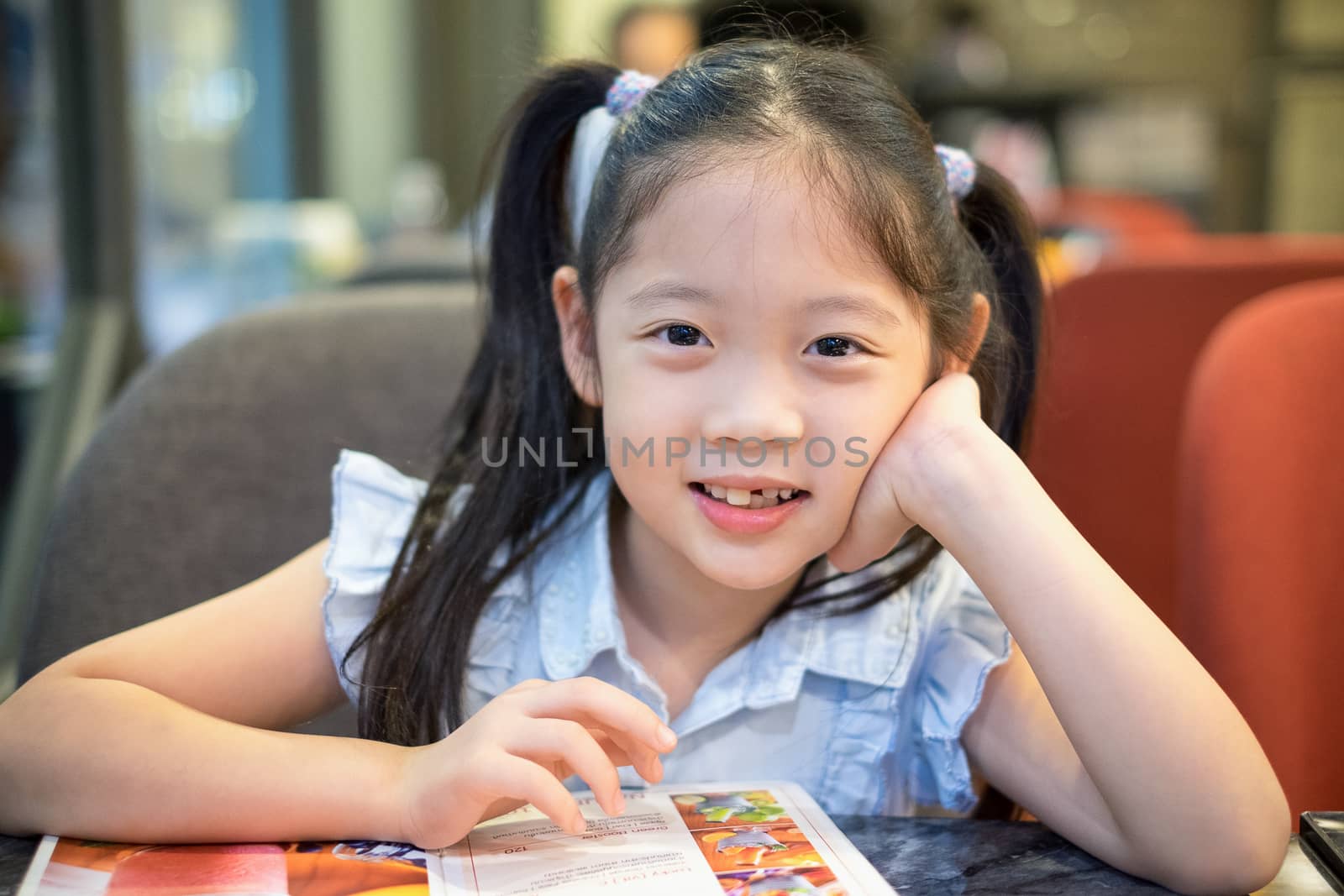 Smiling happy child, girl, sitting a restaurant.