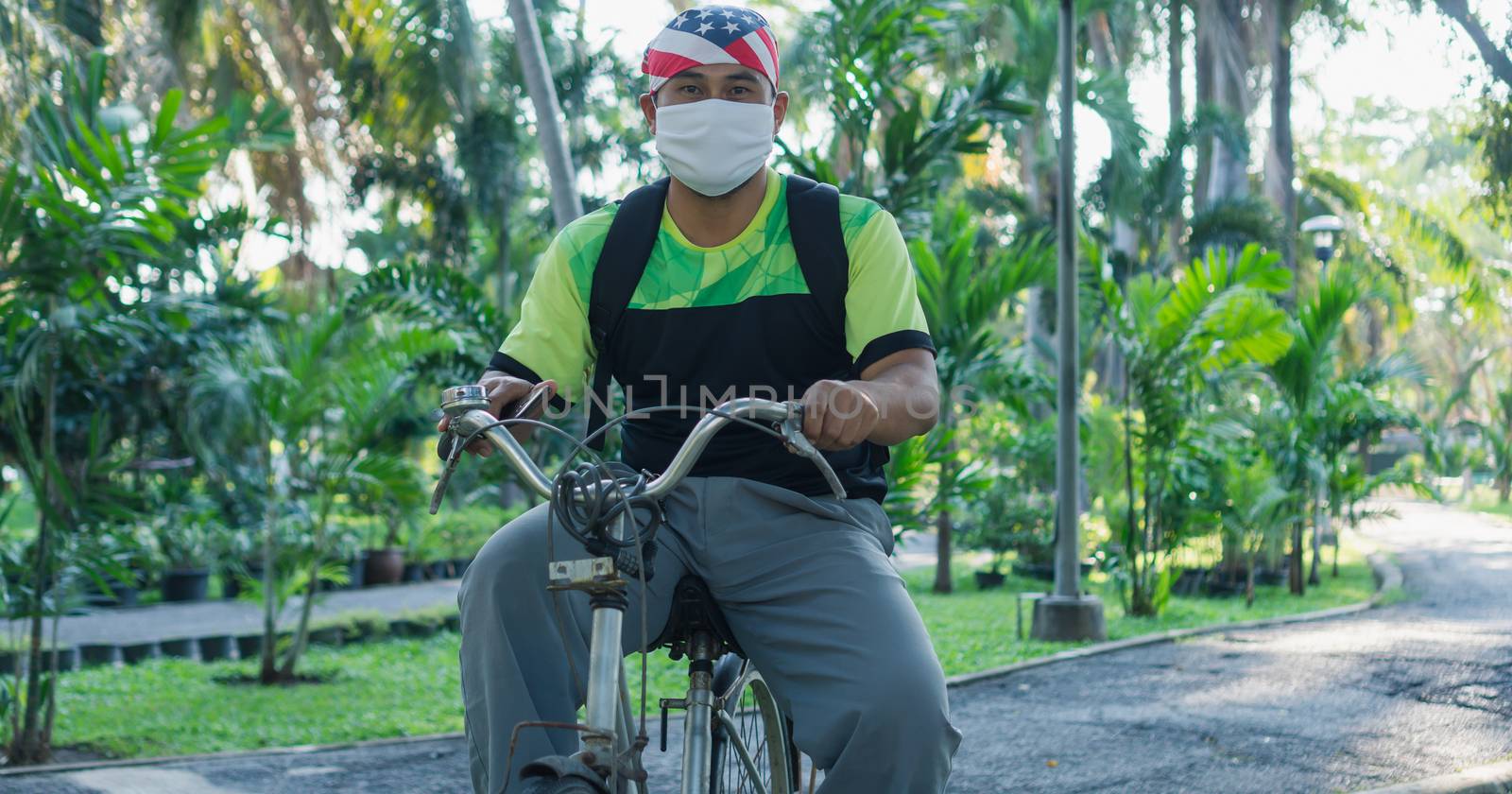 Asian male workers wear masks to prevent and stop infection Virus. Biking in a public garden makes the body immune to disease.