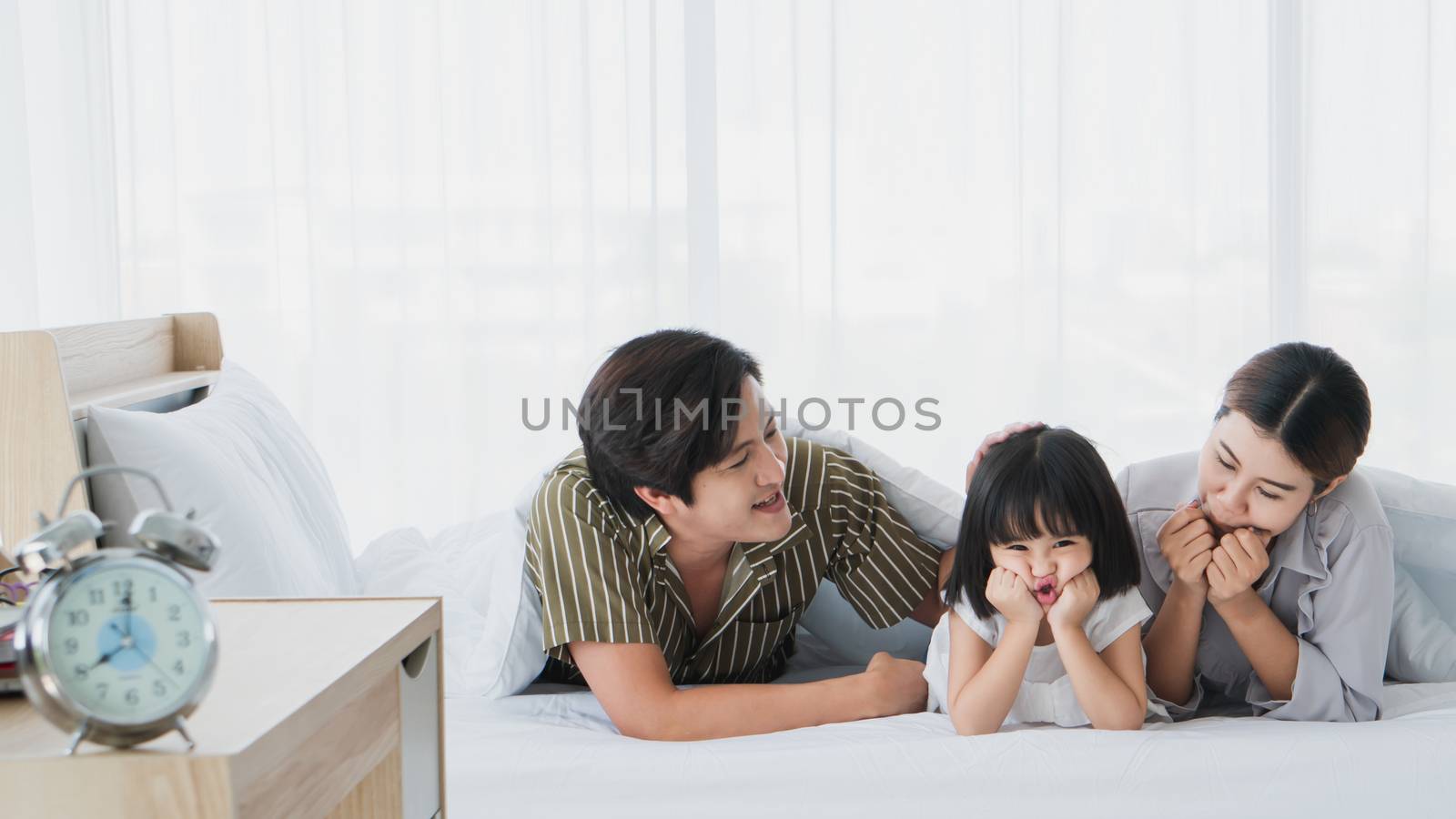 Photos of warm and lovely Asian families. Parents are playing happily and happily with their little daughter in the bedroom. Being happy to be with family on holidays