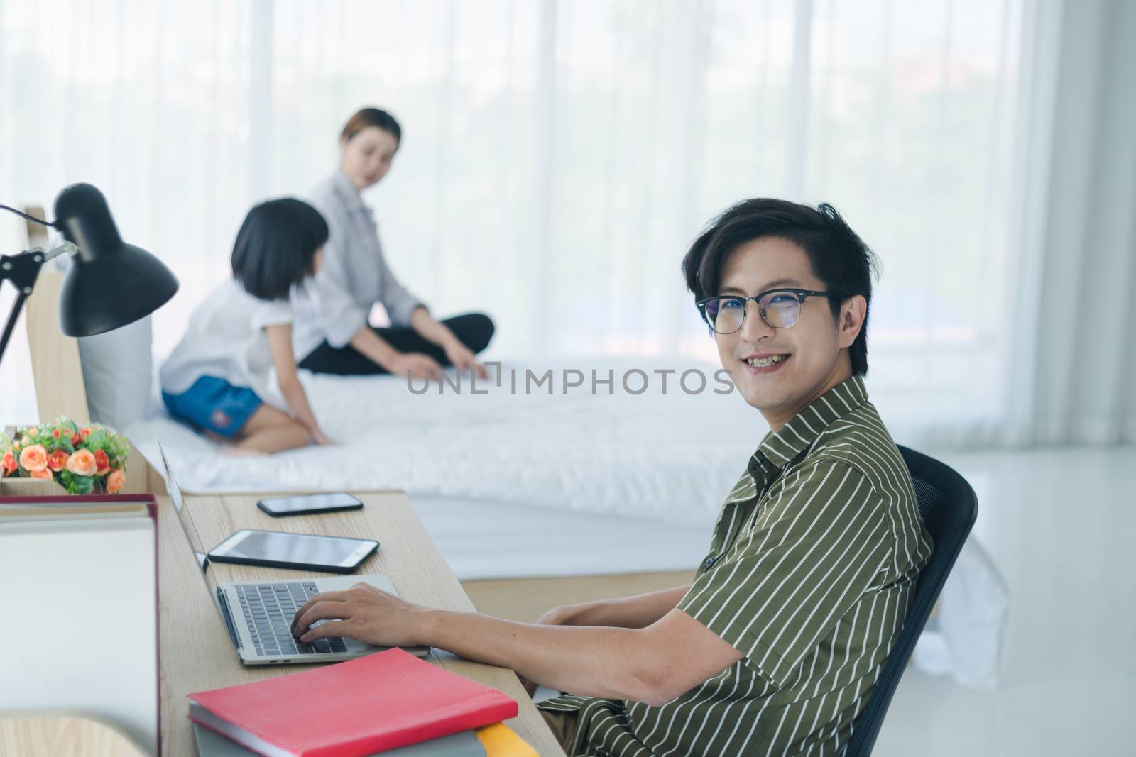 Work  from home - Concept. Photos of Asian families consisting of parents and daughters. Parents working at home and raising children as well. The little daughter who is playing mischievously