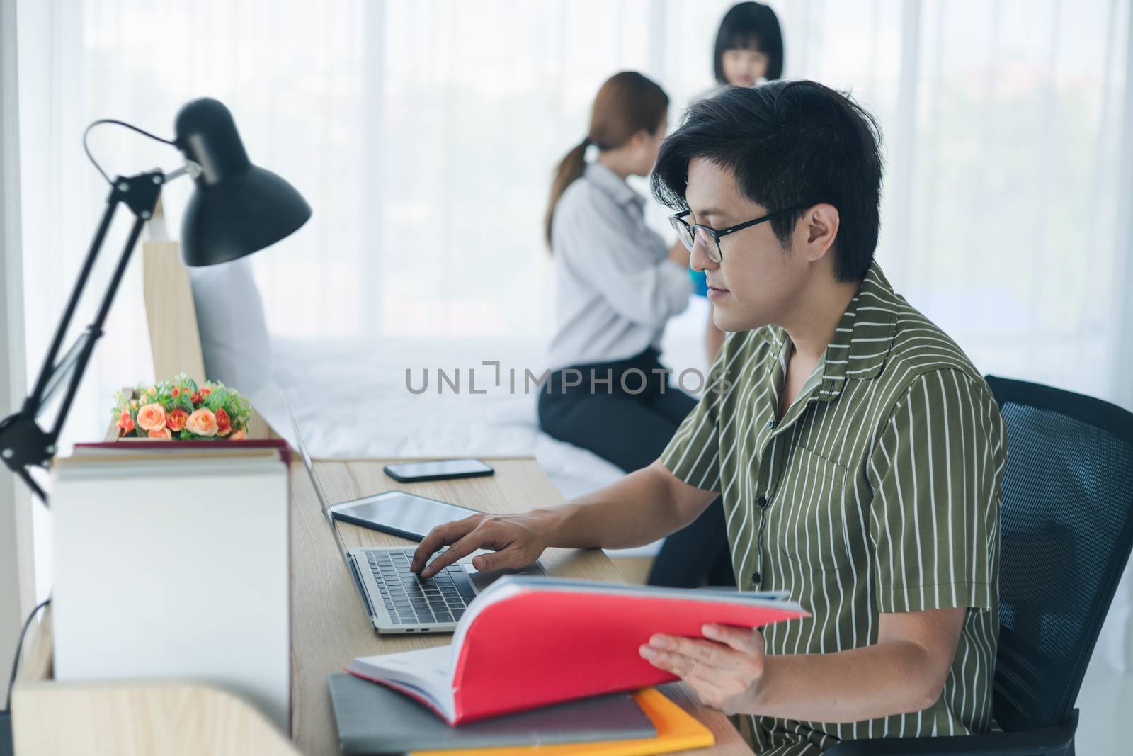 Work  from home - Concept. Photos of Asian families consisting of parents and daughters. Parents working at home and raising children as well. The little daughter who is playing mischievously