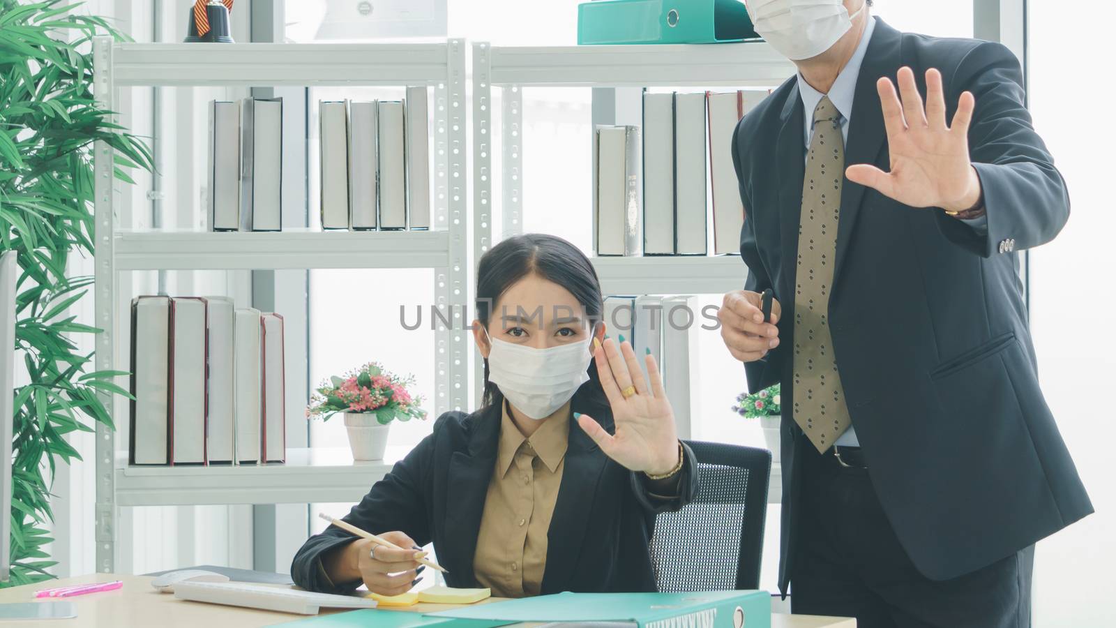 A team of Asian businessmen wear masks to protect and prepare to fight the pandemic virus worldwide. A team of Asian businessmen wearing black suits are working together in the office.