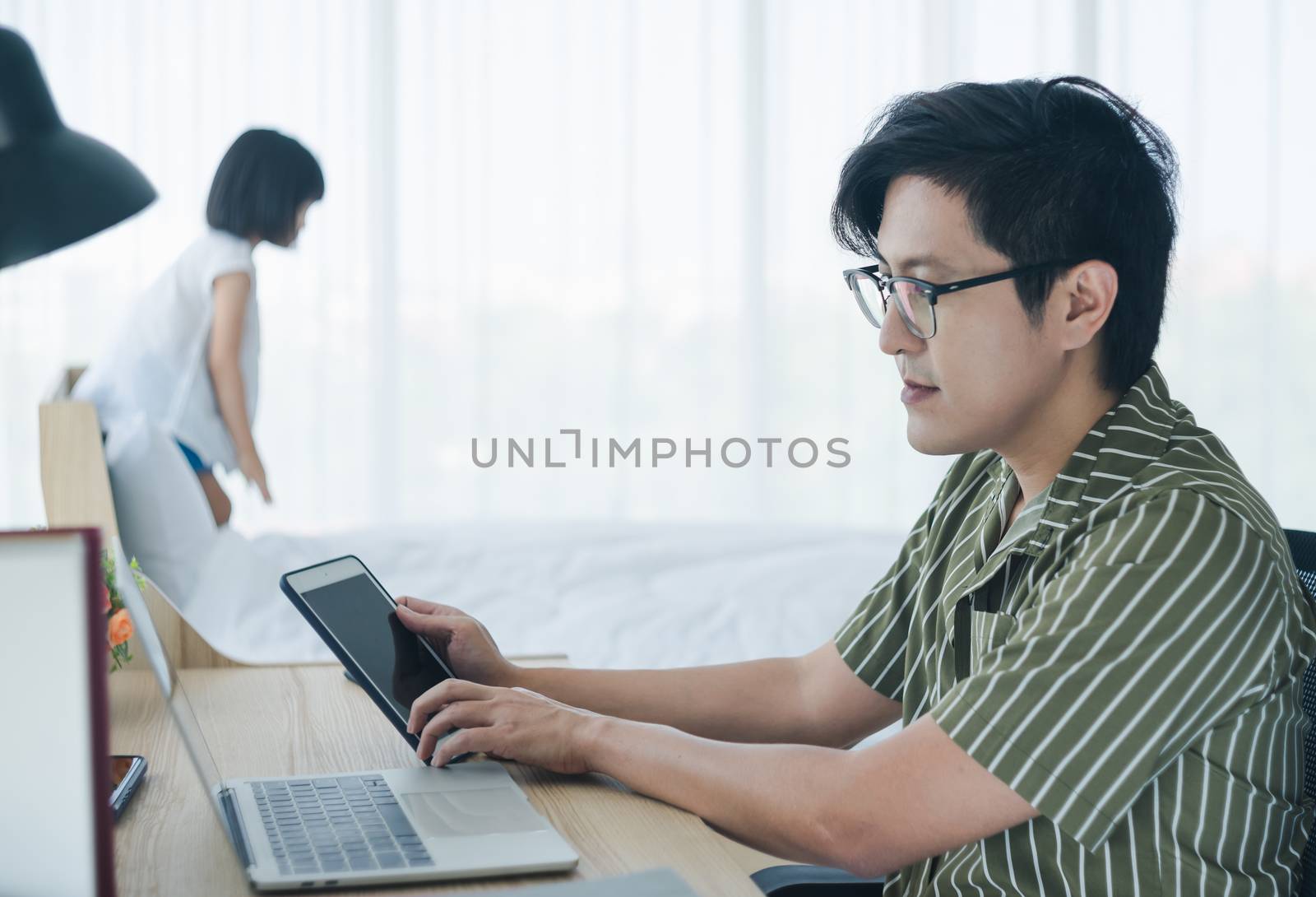 Working from home - Concept. Photos of Asian families. The modern father is working at home and raising children. The little daughter who is playing mischievously