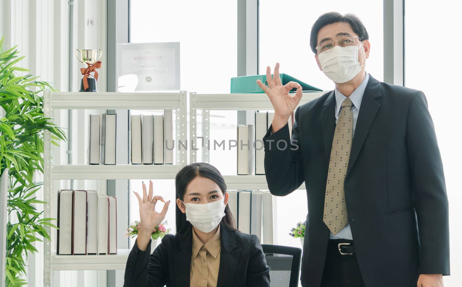 A team of Asian businessmen wear masks to protect and prepare to fight the pandemic virus worldwide. A team of Asian businessmen wearing black suits are working together in the office.