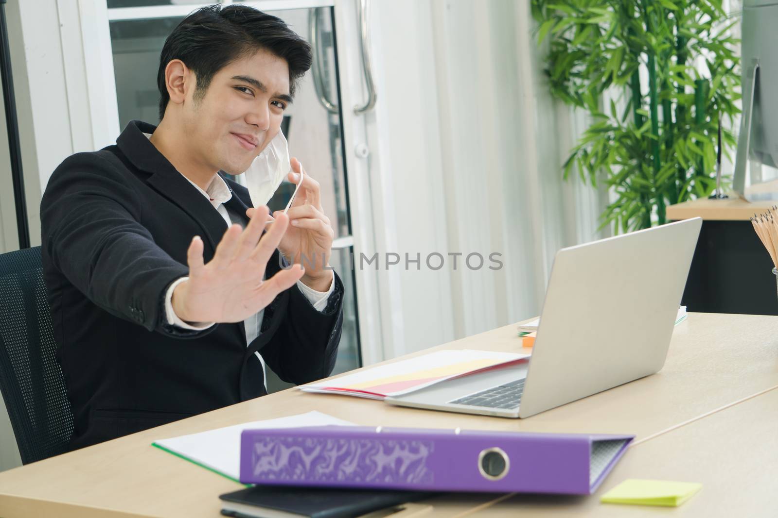 Asian business men wear masks to protect and prepare to fight the pandemic virus worldwide. An Asian business man wearing a black uniform working in an office.