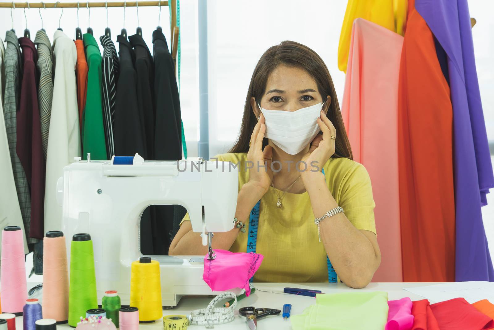 An Asian designer and tailor is working in the room. She wears a mask to protect against dust and prevent infection. From the outbreak of the corona virus That is currently spread throughout the world