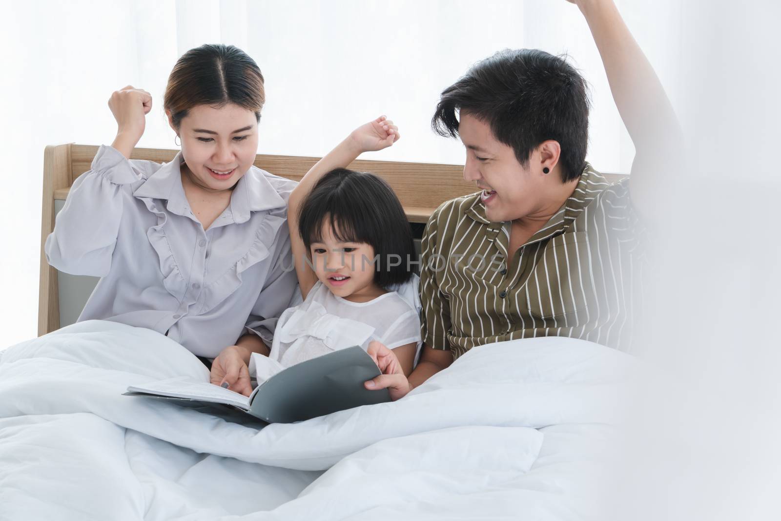 Photos of warm and lovely Asian families. Parents are playing happily and happily with their little daughter in the bedroom. Being happy to be with family on holidays