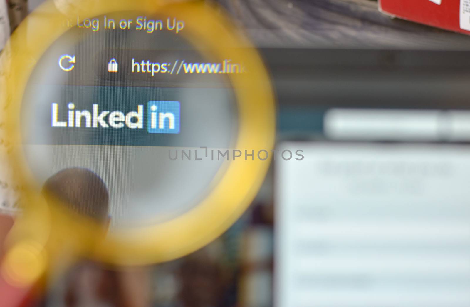 New York, USA, 2020. Linkedin website signup page through a magnifying lens. Out of focus laptop screen is in the background. Concept social network