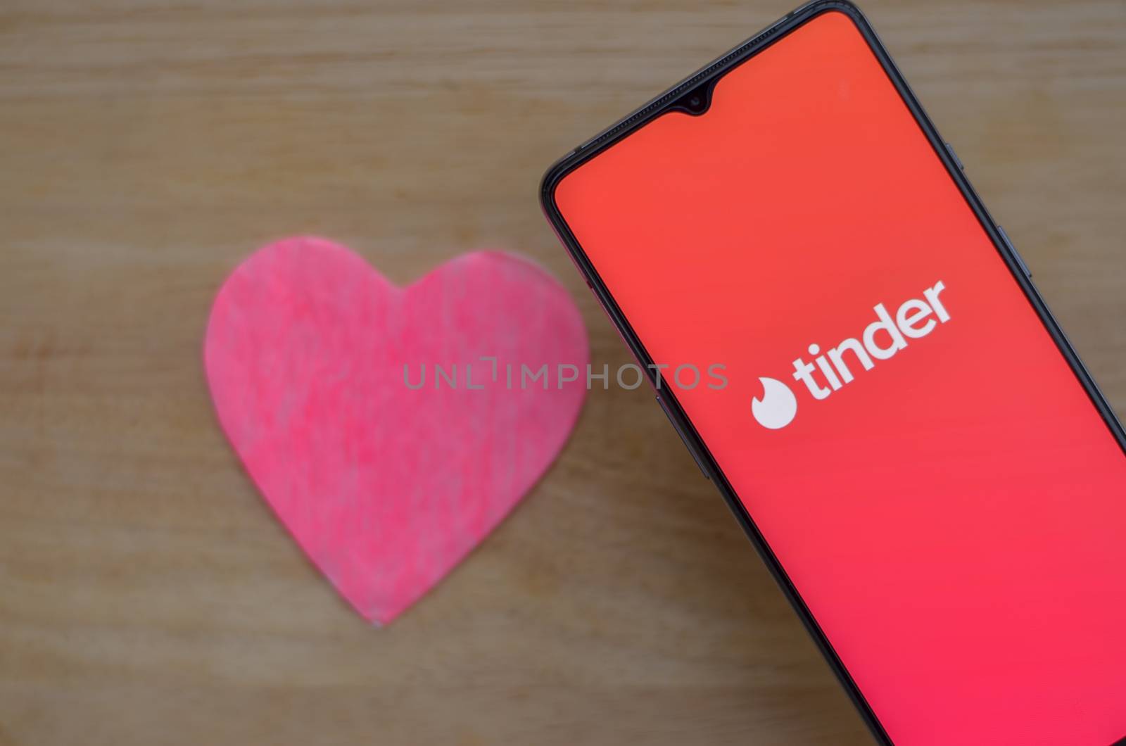 New York, USA, 2020. Flat lay with Tinder app logo on a smartphone screen with a pink heart on a wooden background on display. Tinder is an online social search and dating mobile phone app