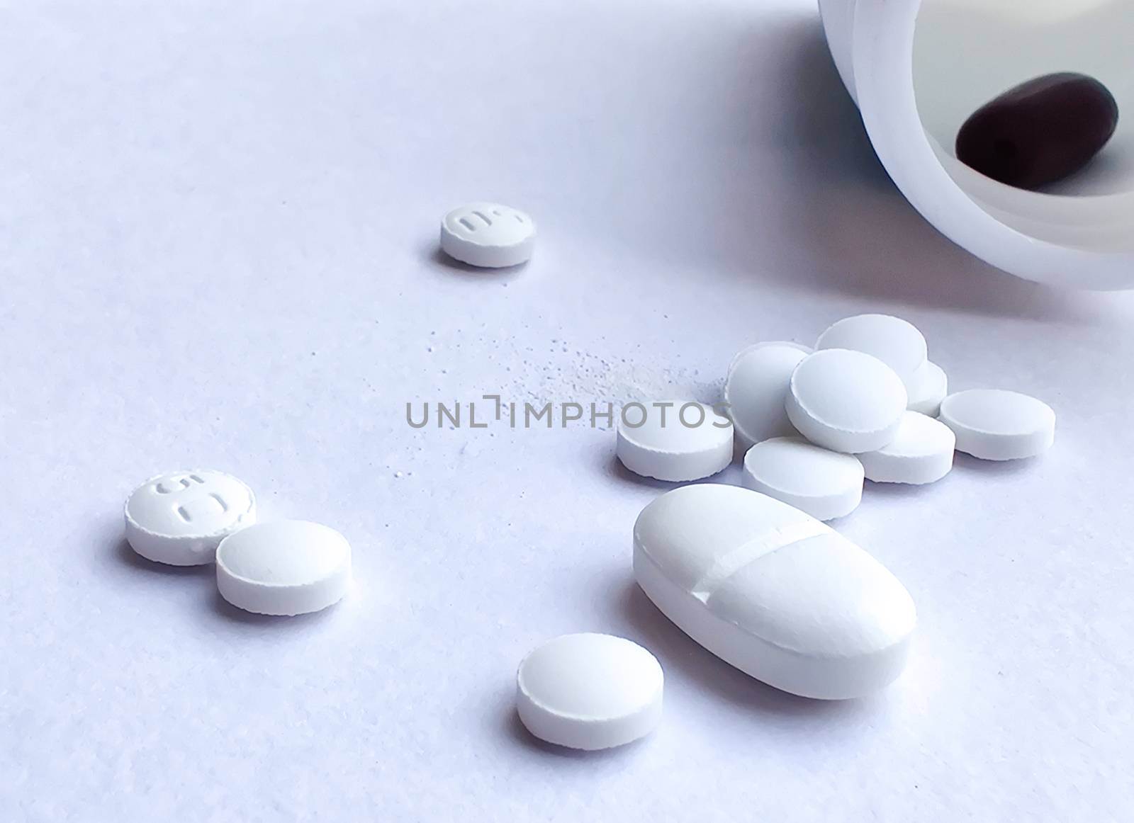 Pills spilling out of a plastic bottle and isolated on white background. Top view with copy space. Medicine concept