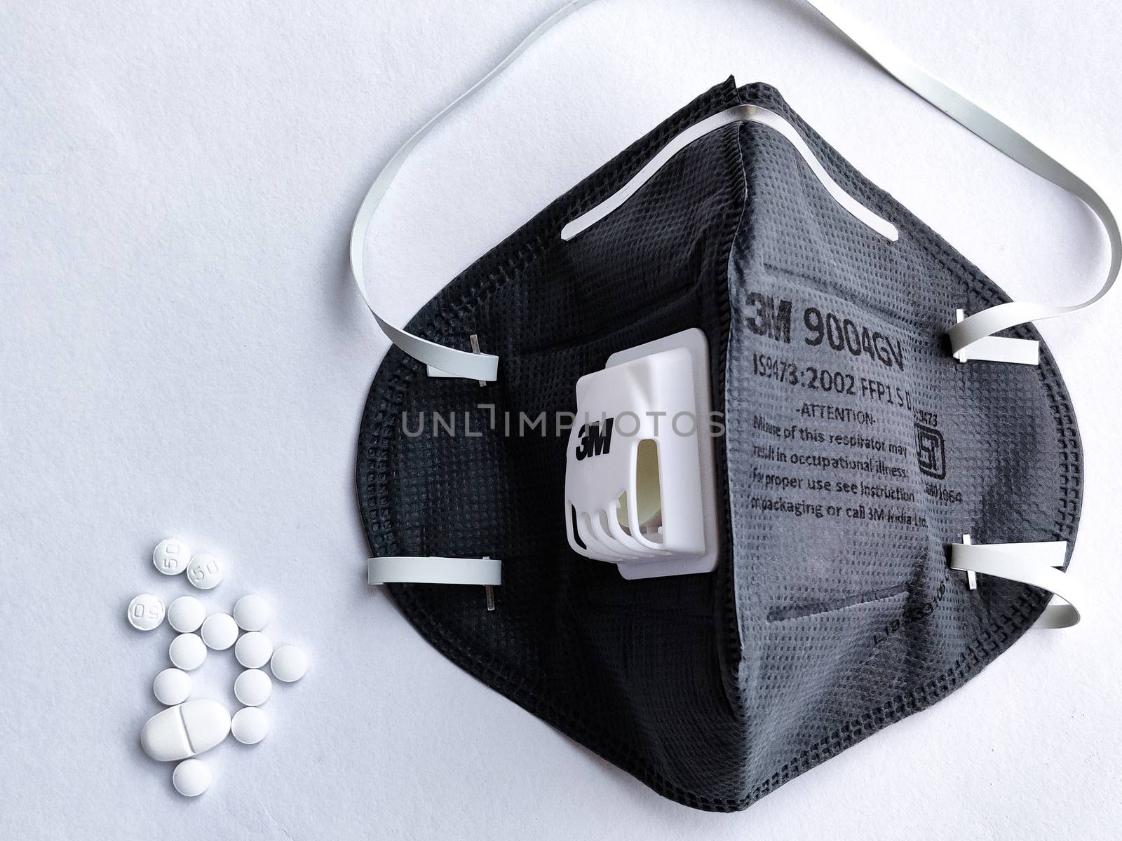 New Delhi, India, 2020. Selective focus of 3M Grey N95 face mask on a white background with medicine tablets for safety against Corona virus (Covid-19) pandemic to reduce the rate of spread