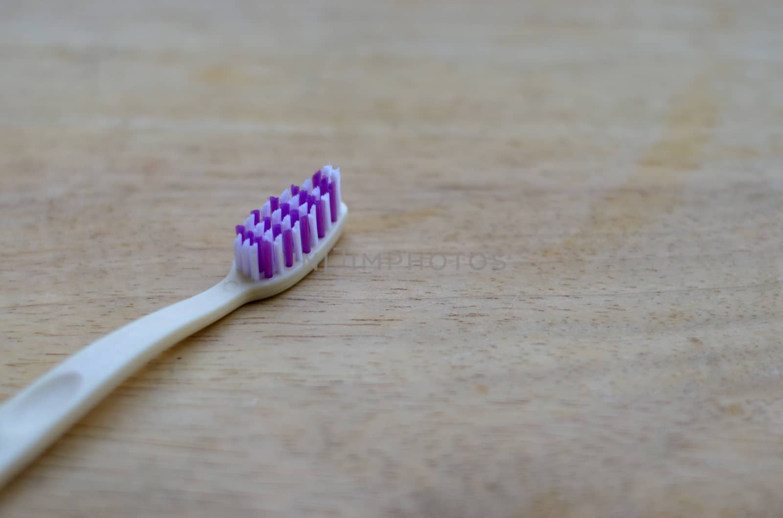 White or cream colored bamboo toothbrush on wood background. Zero waste, biodegradable material, concept - Save the environment by jayantbahel