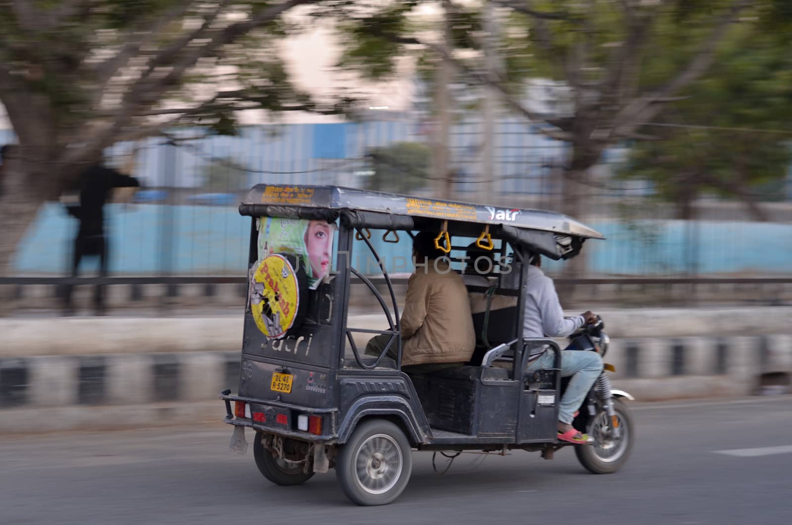 Delhi, India, 2020.Panning shot of a speeding e- rickshaw on Delhi roads. Electric rickshaws are economical mode of transportation in India for last mile travel. Battery capacity increasing gradually.