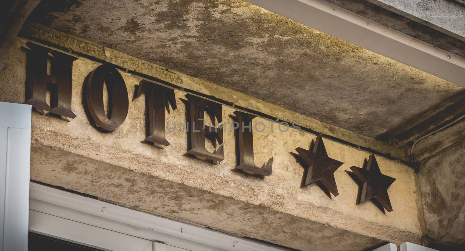 hotel sign on a stone wall with two stars in France