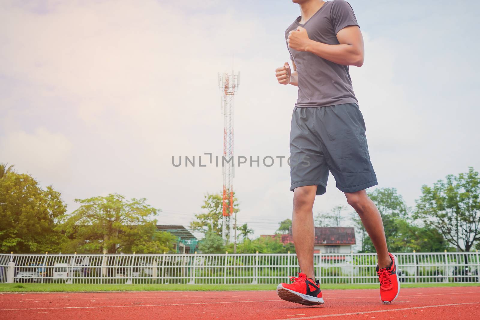 Young man jogging in the morning sun in the stadium. by numberone9018