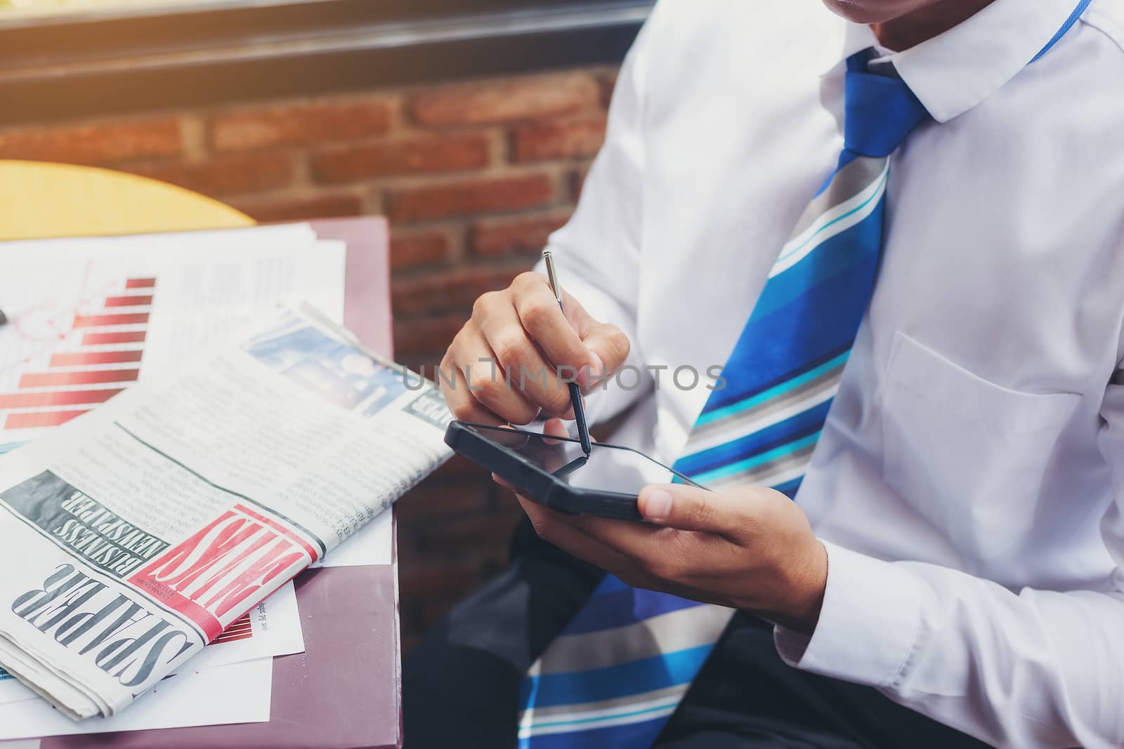 A handsome businessman reading a text from a mobile phone while sitting in a coffee shop.