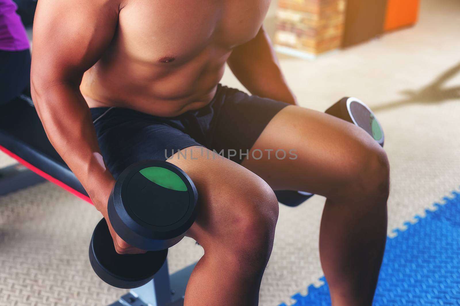 handsome man exercising by lifting a dumbbell for health care in a public gym. Health care concept