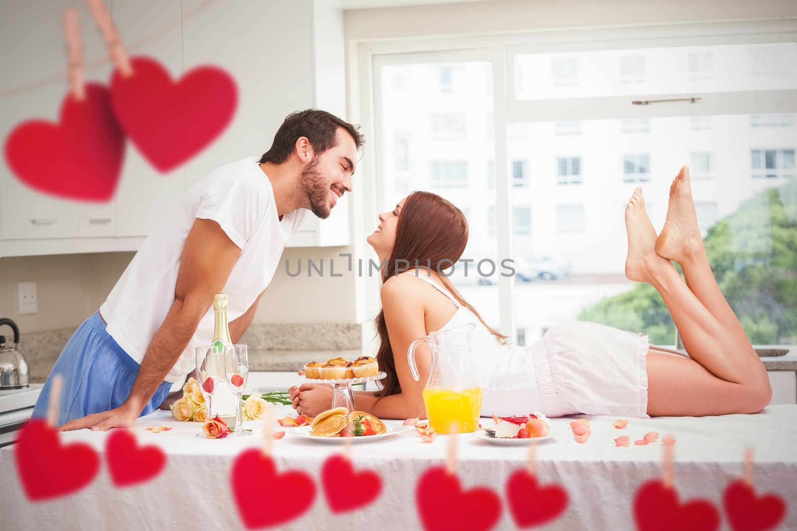 Young couple having a romantic breakfast against hearts hanging on a line