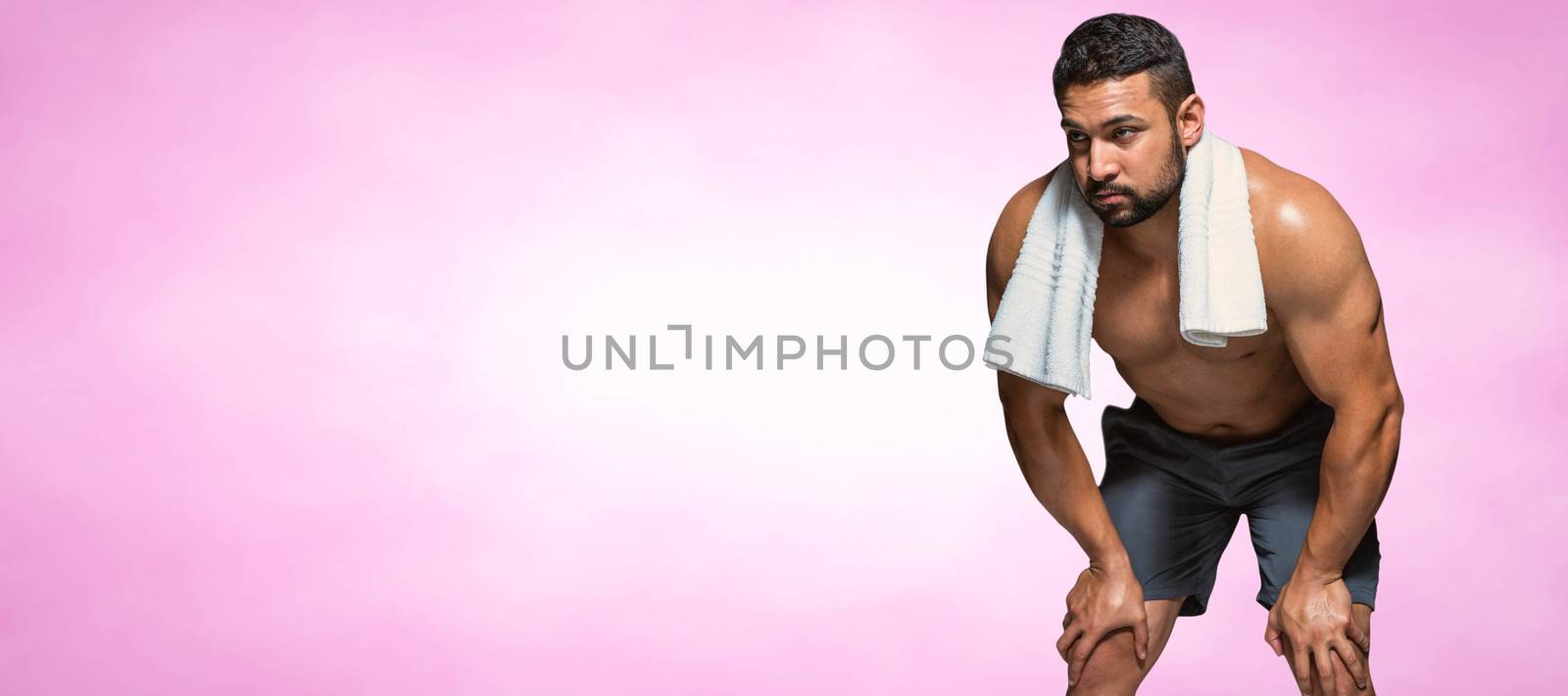 Bodybuilder man with hands on thighs against pink background