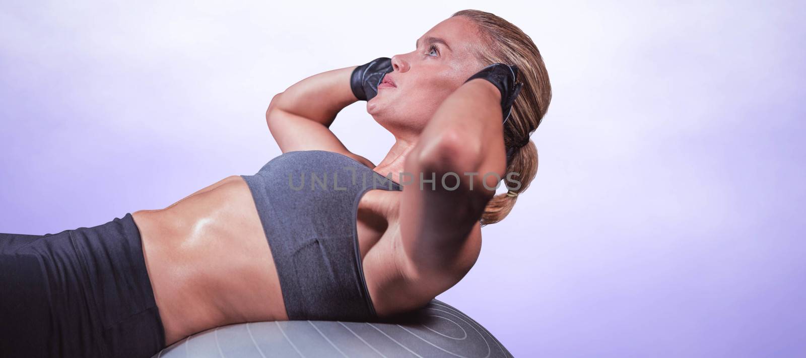 Muscular woman doing sit ups against purple background