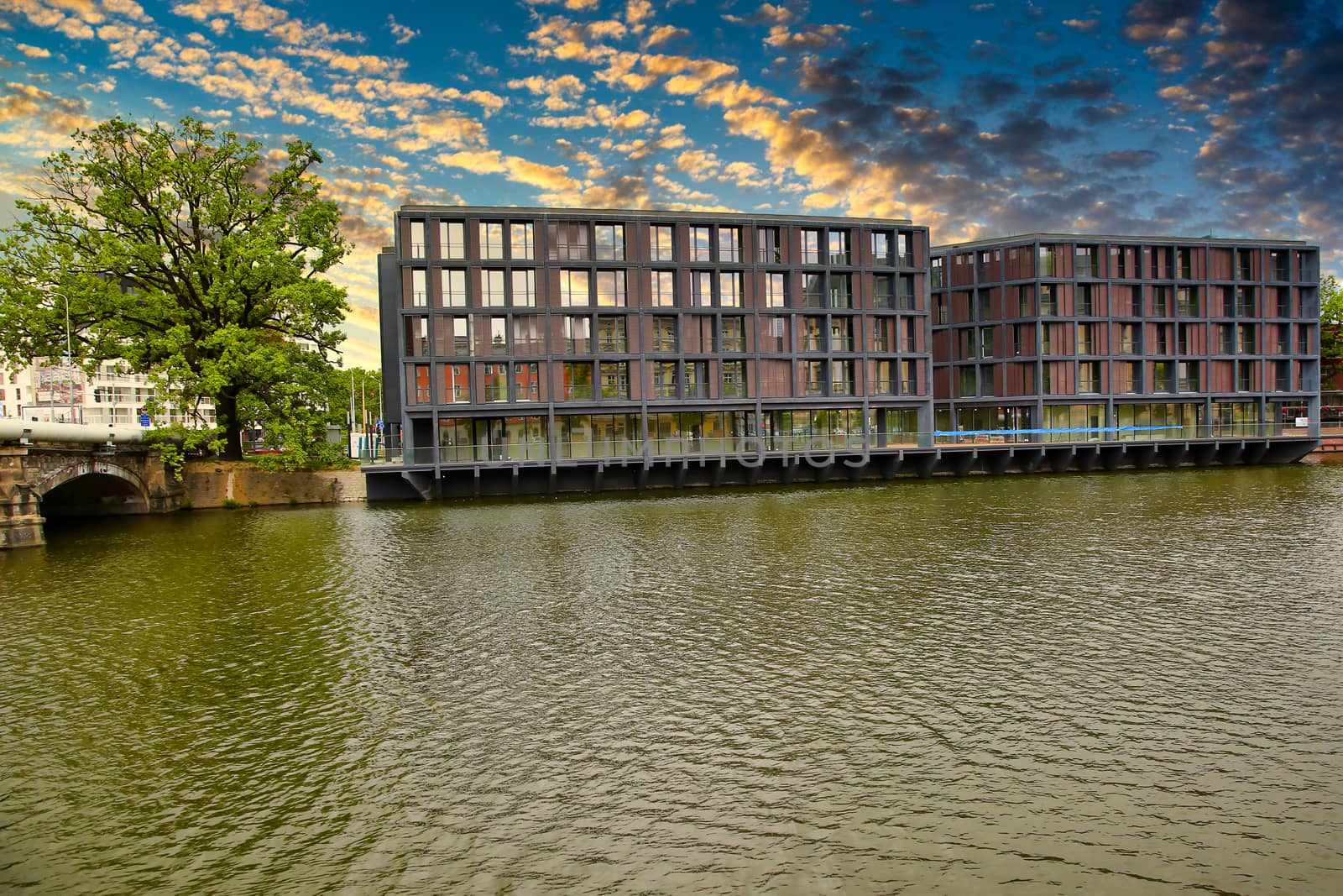 Wrotclaw, sky reflection in the windows of a building on the river bank