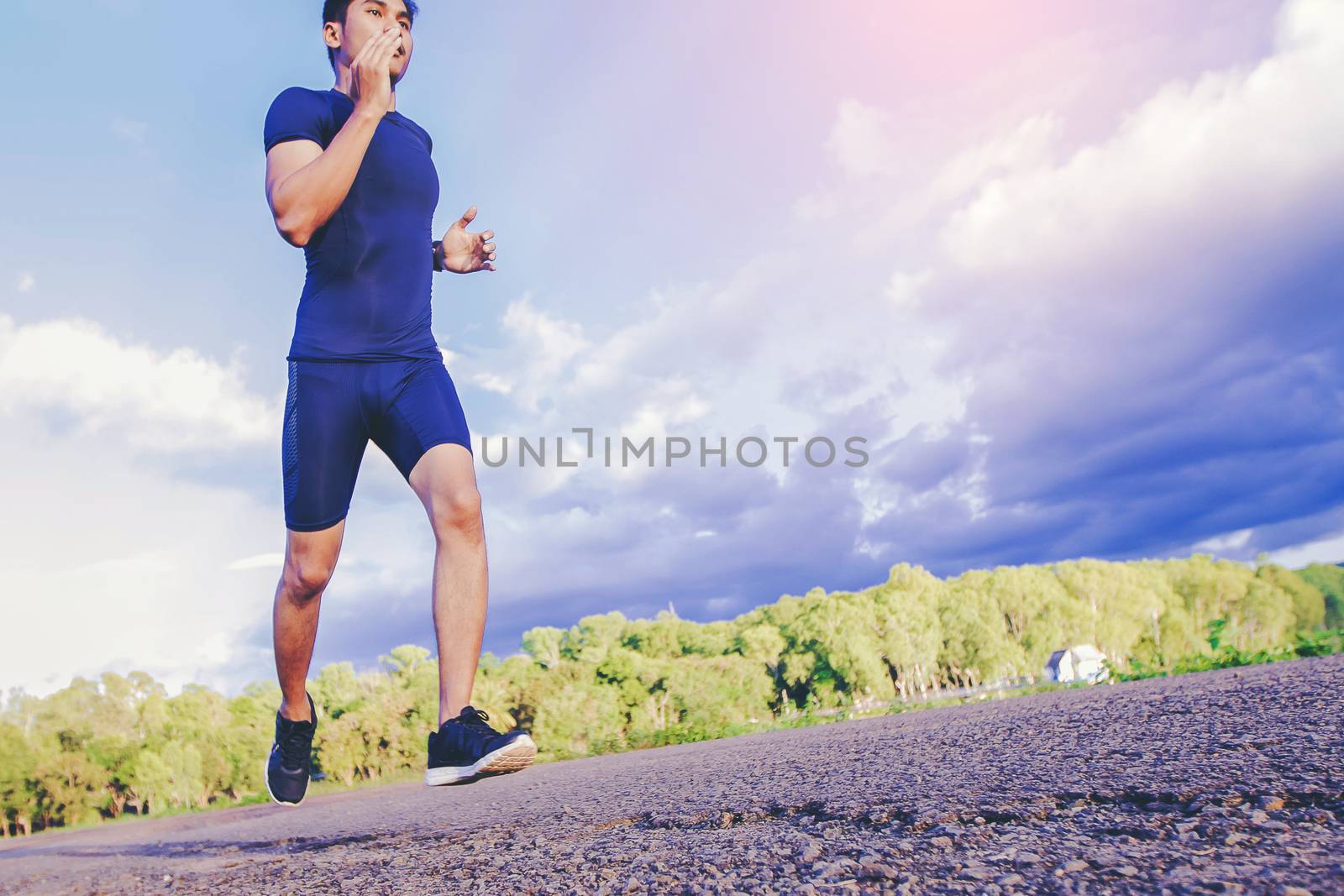 handsome man running on a rural road during sunset