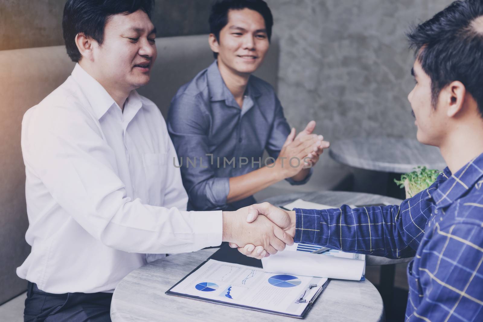 Businessmen negotiate in a coffee shop. Hold hands and greet before the business talks comfortably.