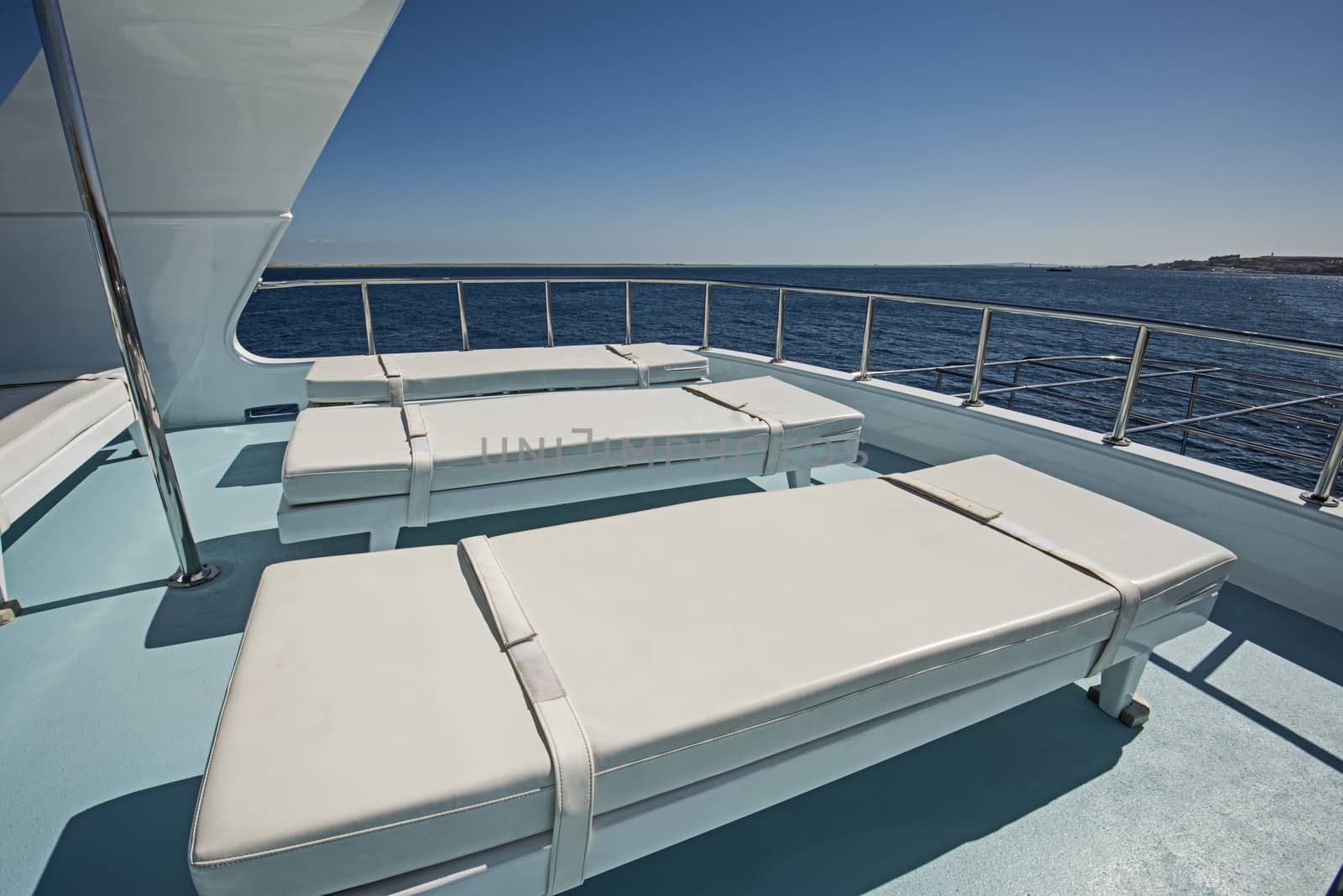View over the sundeck of a large luxury motor yacht on tropical open ocean with sun loungers