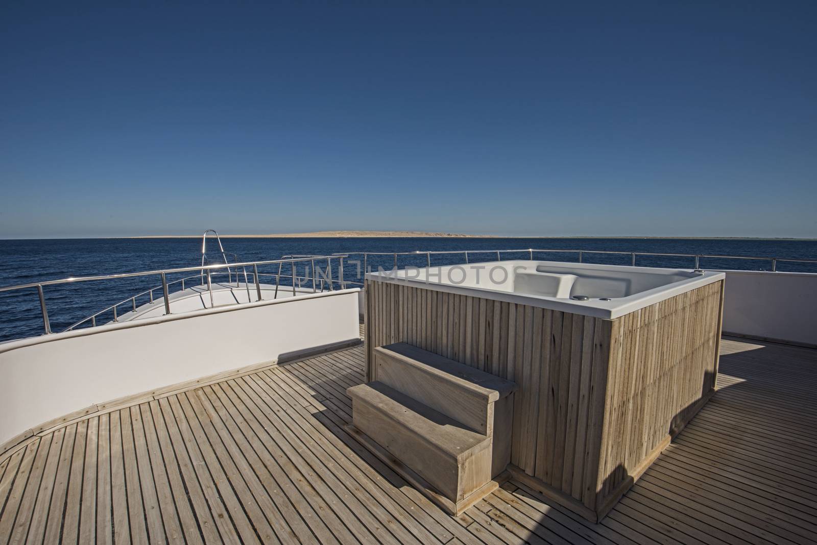 View over the bow of a large luxury motor yacht on tropical open ocean with hot tub