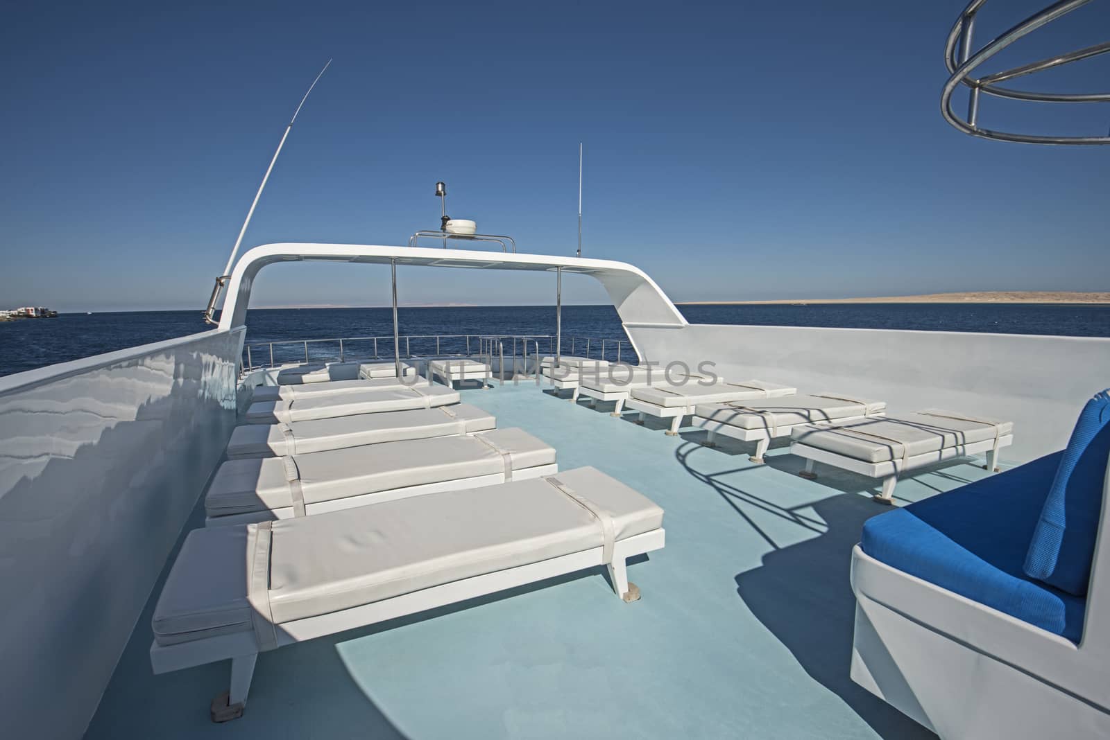 View over the sundeck of a large luxury motor yacht on tropical open ocean with sun loungers