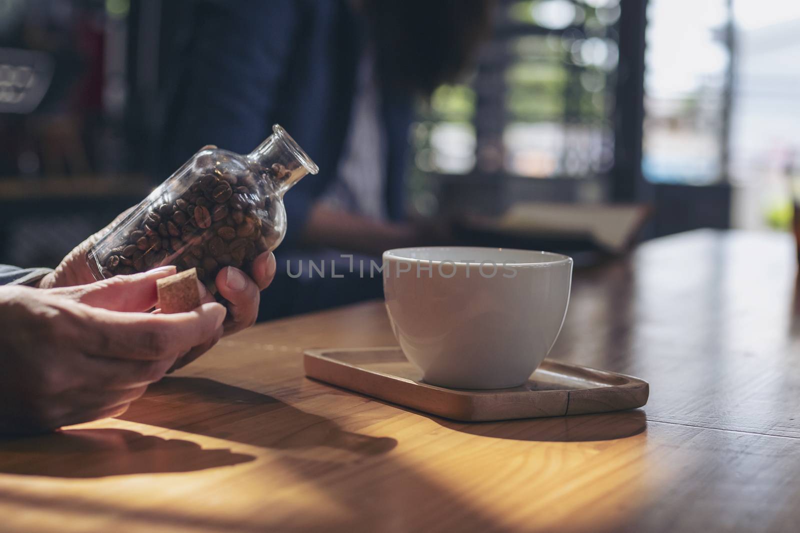 Close-up image of hand holding coffee beans in glass bottles