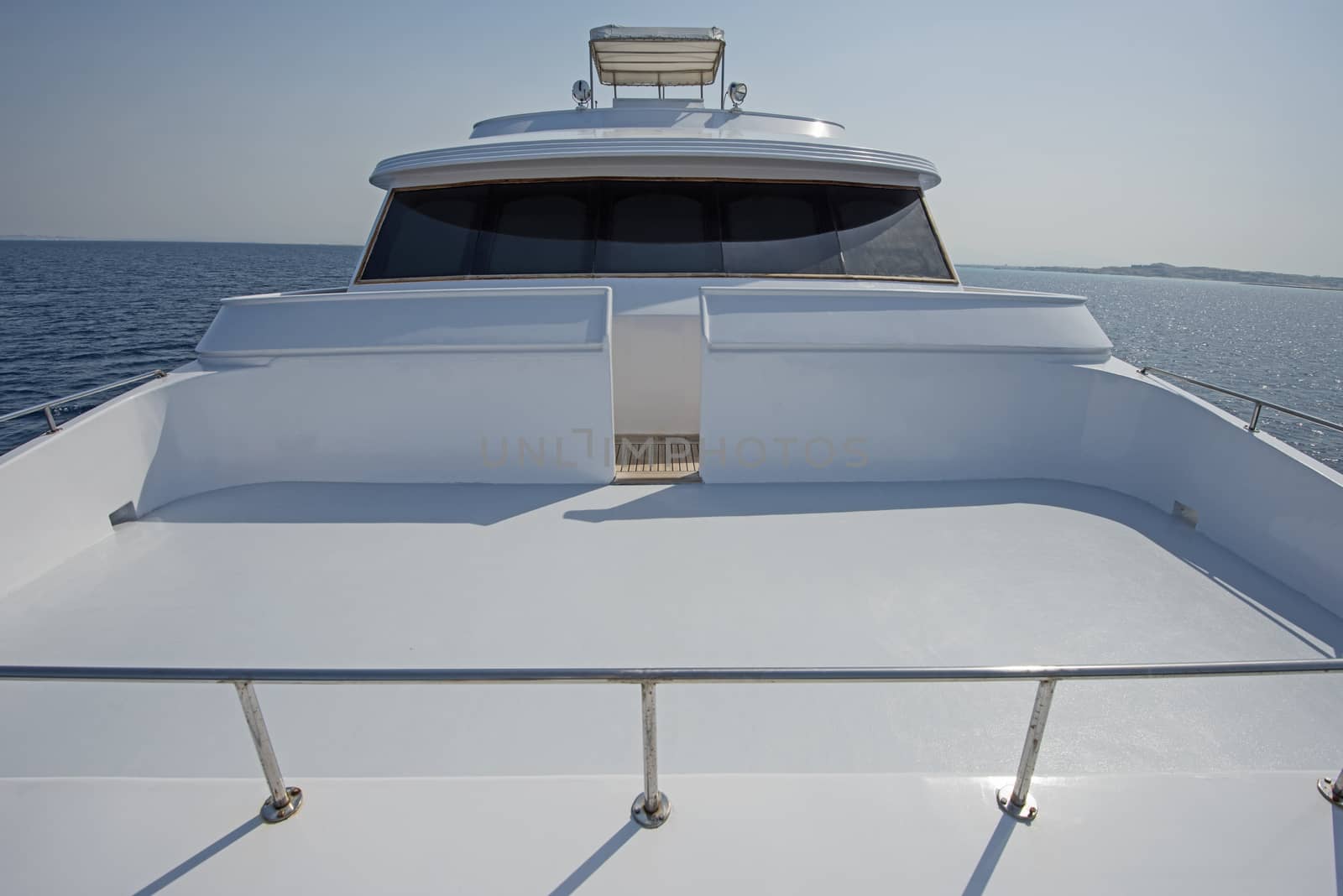 View over the bow of a large luxury motor yacht with flybridge on tropical open ocean