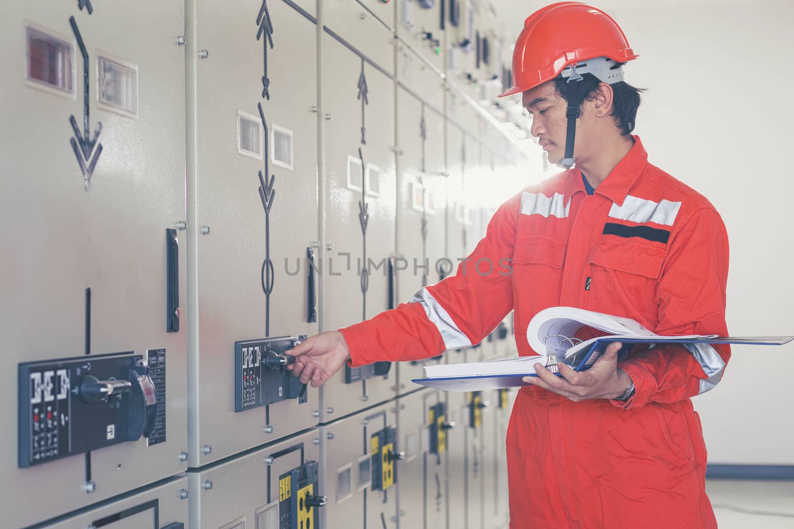 A handsome electrician is checking the electrical equipment to prepare it for use.